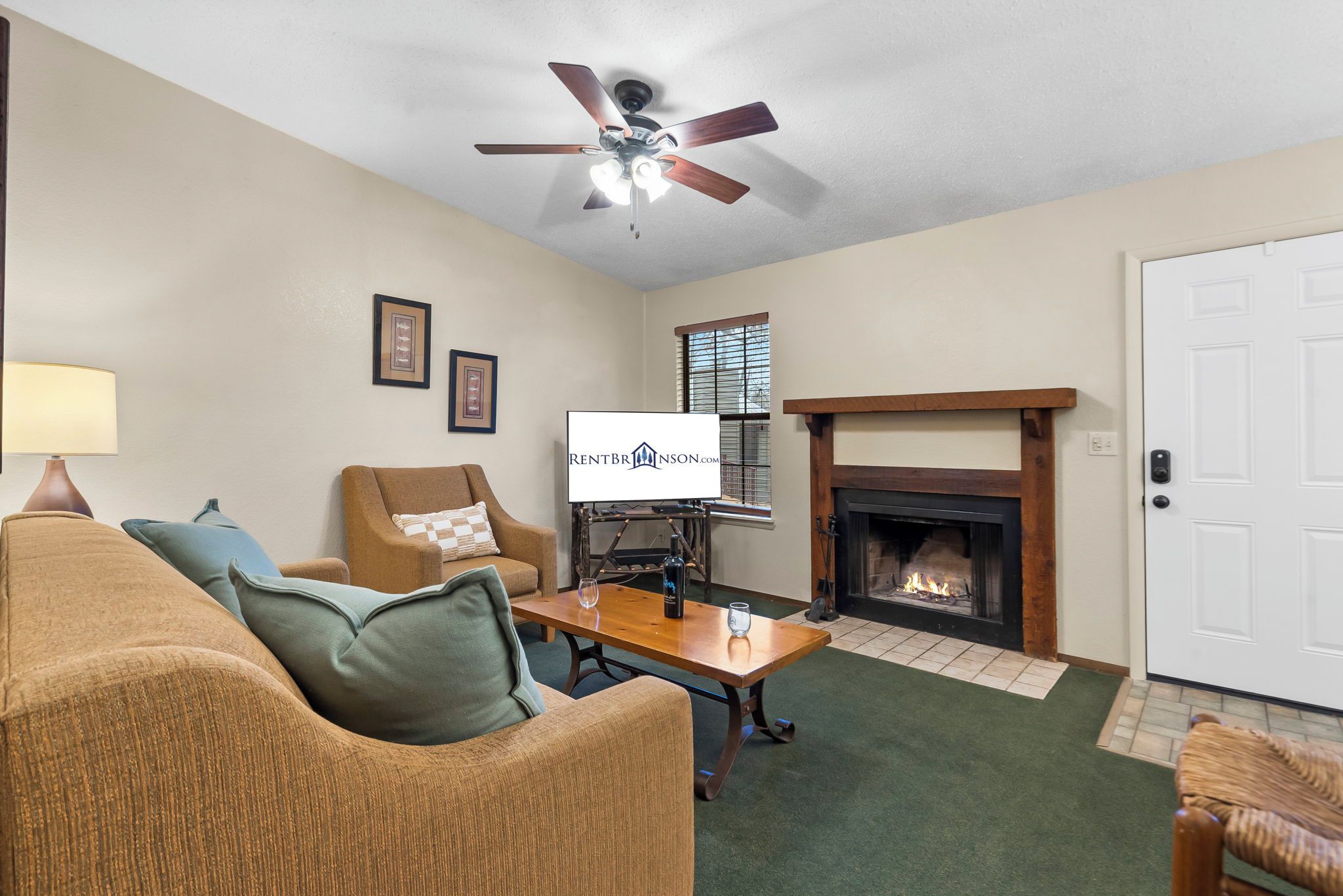 Un salon avec une cheminée, un ventilateur de plafond et un panneau décoratif encadré.