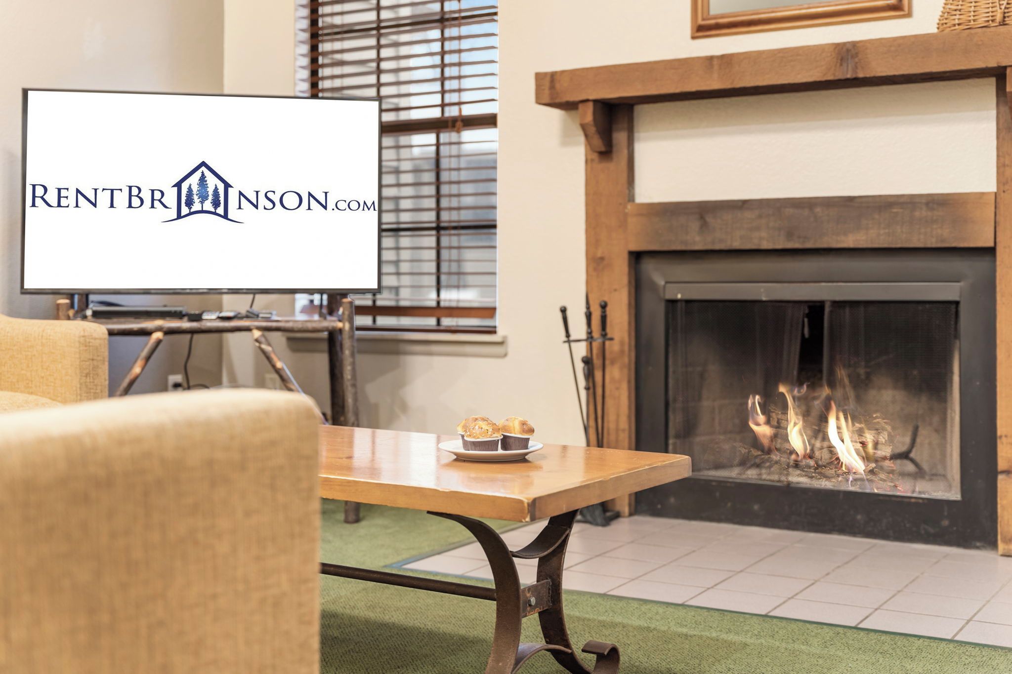 A living room with a fireplace, a television, and a table with muffins.