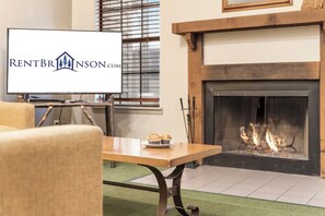 A living room with a fireplace, a television, and a table with muffins.