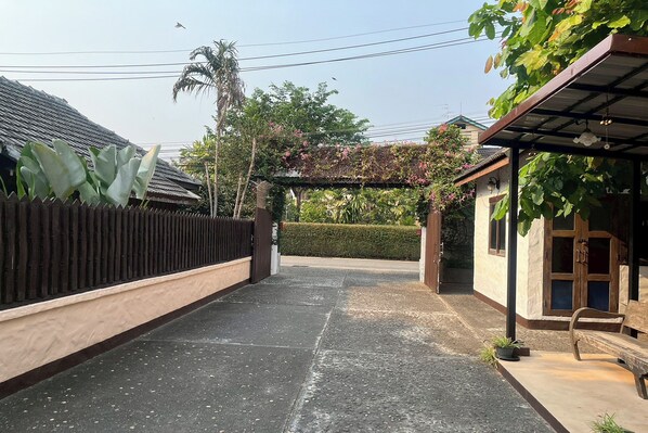 Une cour avec un chemin pavé, une clôture en bois et un banc.