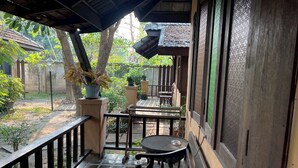 A covered outdoor area with a wooden table and chairs, potted plants, and a view of the surrounding garden. - The Royal Shilton Resort (Chiang Mai)