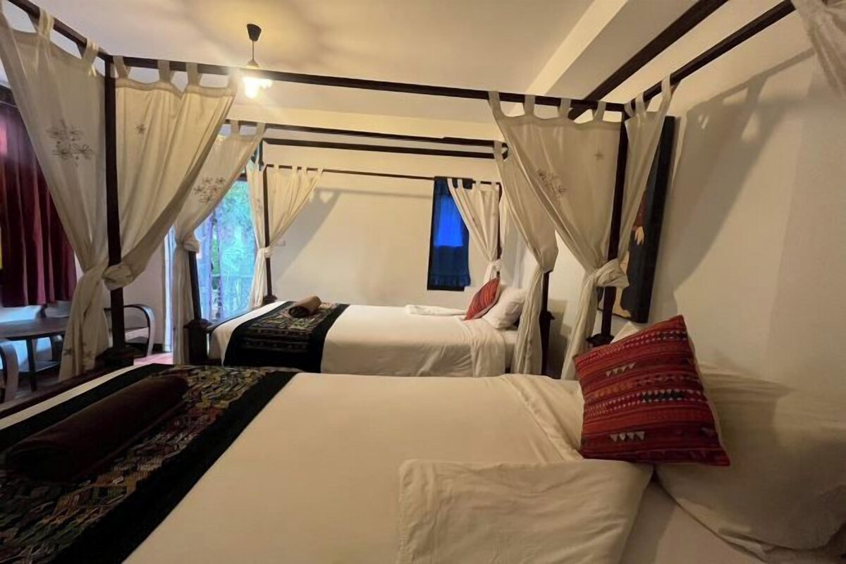 A hotel room with two beds, a large window, and a view of the outdoors.