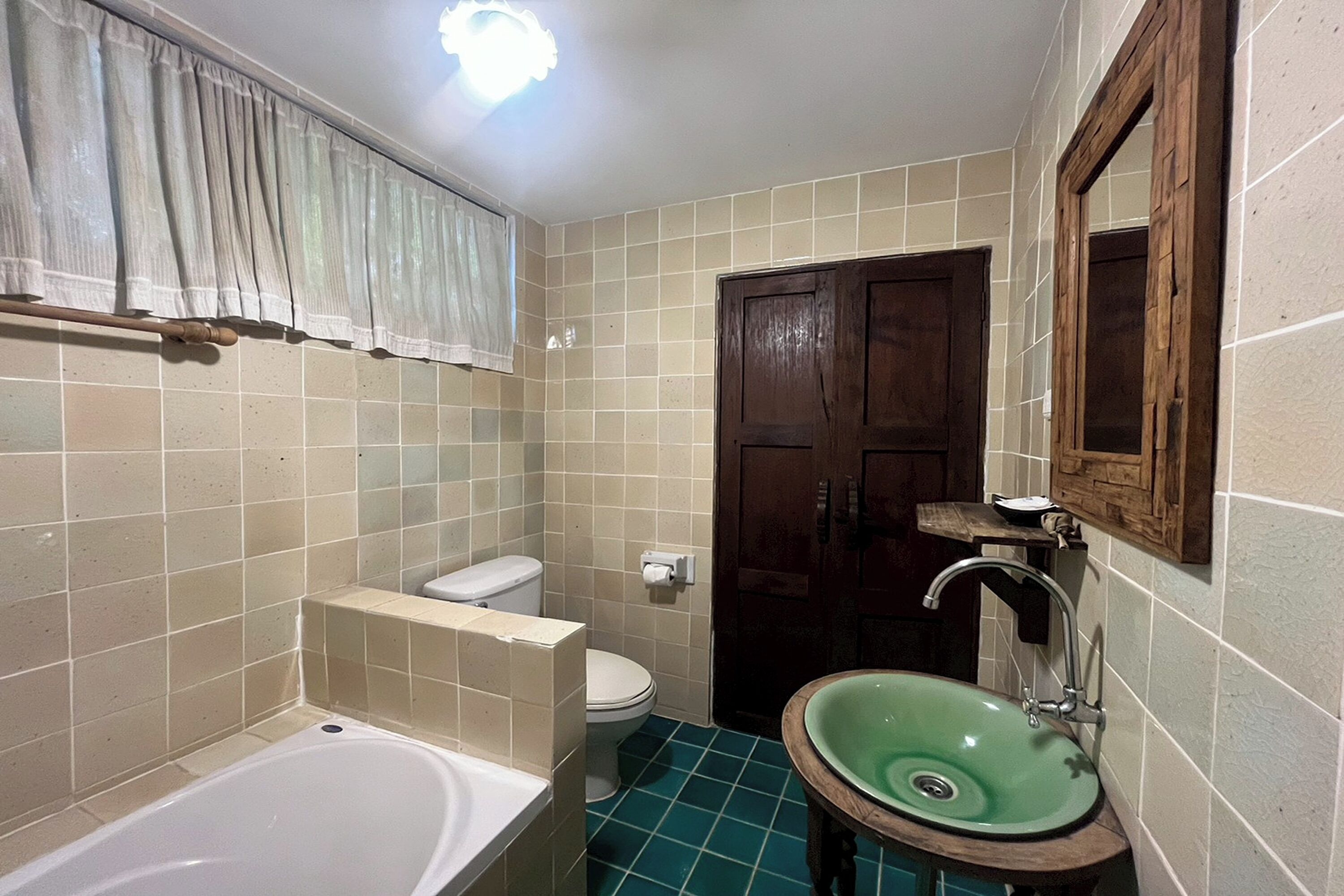 A bathroom with a bathtub, toilet, sink, and a wooden door.