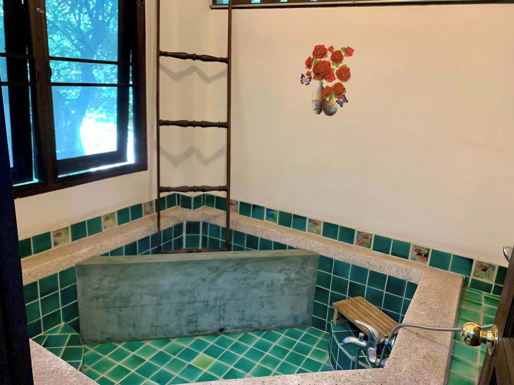 A bathroom with a bathtub, a window, and a decorative wall piece.