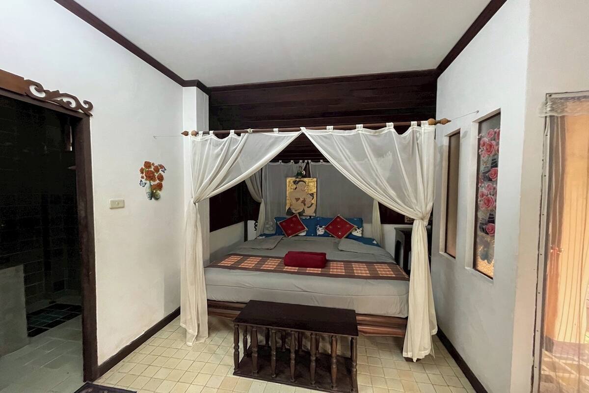 A bedroom with a canopy bed, a small table, and a wall-mounted artwork.