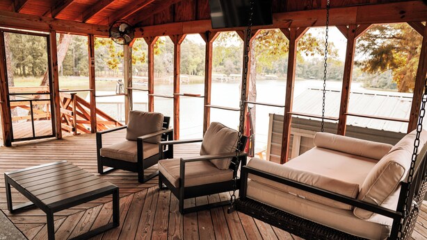 Un espacio al aire libre cubierto con una mecedora, dos sillones y una mesita.