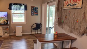 Un comedor con mesa y banco de madera, un televisor y un letrero en la pared que anuncia una tienda de aparejos de pesca.