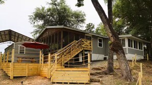 Una cabaña con terraza de madera, una escalera y un espacio cubierto.