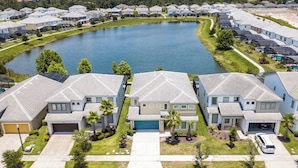 A residential area with modern houses, a central lake, and a well-maintained lawn. - Pool Villa, Game Room, Theater, 20 Minutes to Disney, Great Pool Heat (Kissimmee)