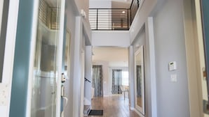 A modern interior with a wooden floor, glass doors, a staircase, and a balcony. - Pool Villa, Game Room, Theater, 20 Minutes to Disney, Great Pool Heat (Kissimmee)