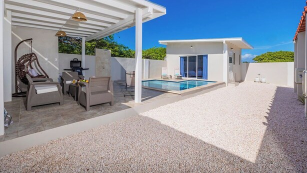 A modern outdoor living area with a pool, covered seating, and a pergola.