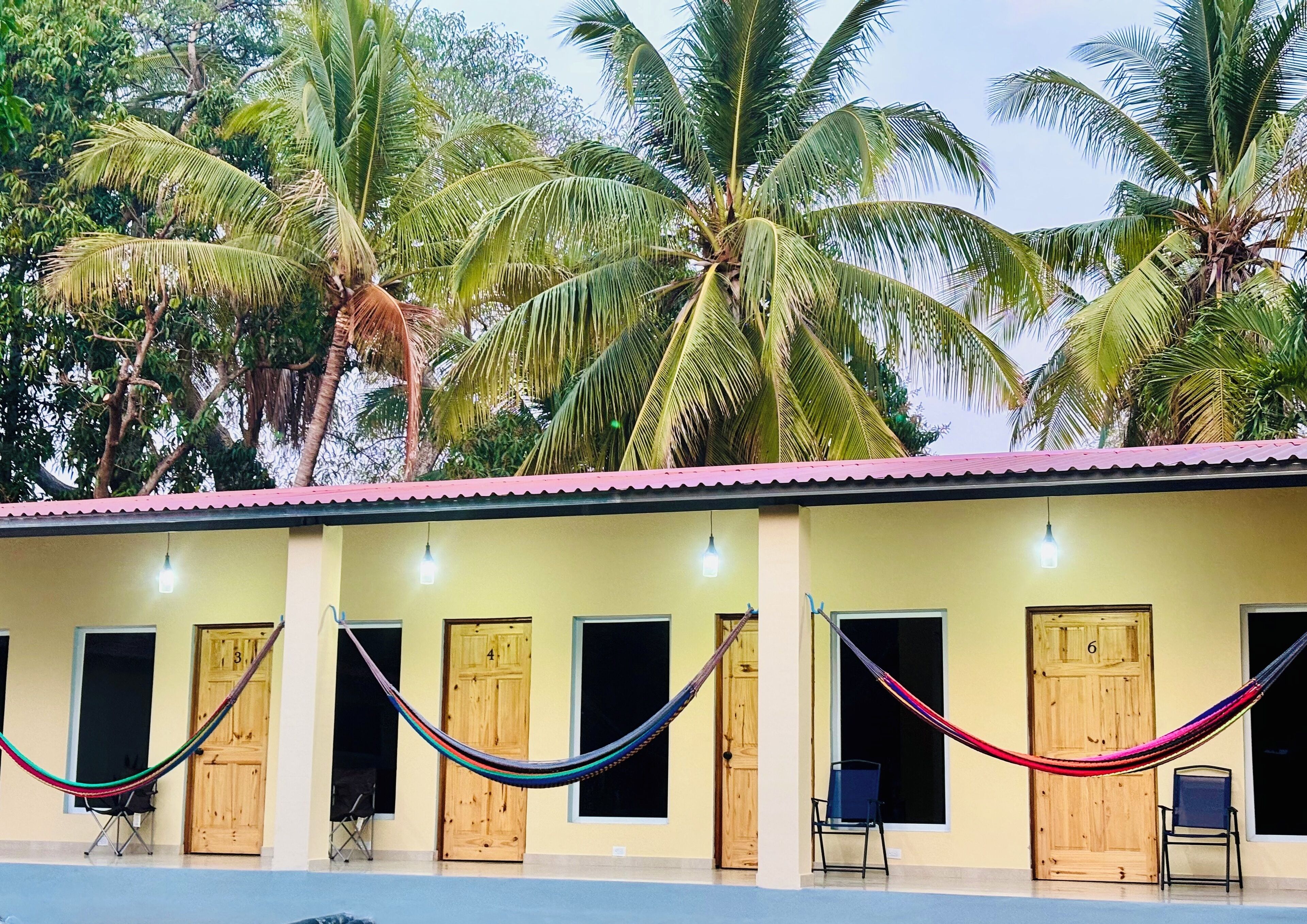 A building with multiple wooden doors, a tiled roof, and a hammock strung across the front.