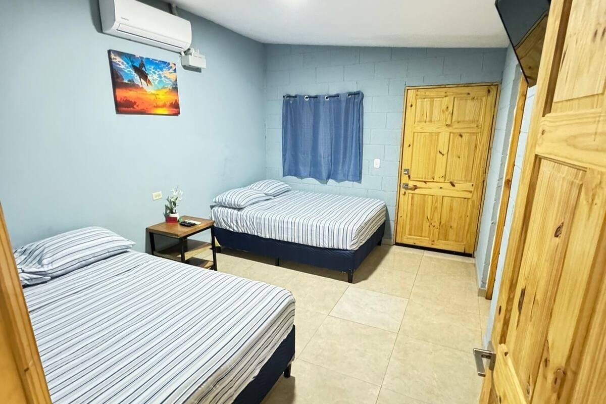 A room with two beds, a small table, a TV, and a wooden wardrobe.