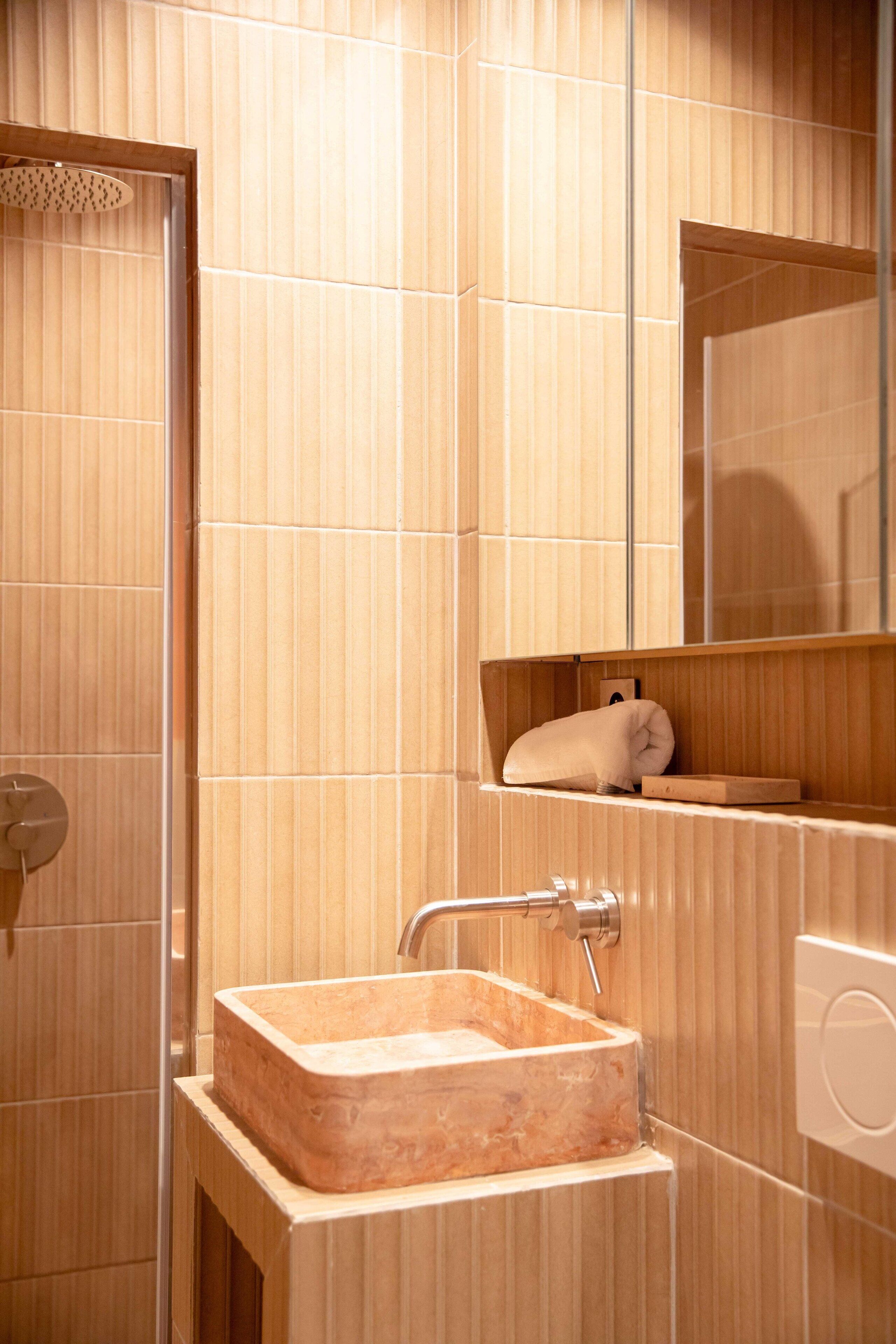 Un baño con tocador de madera, un lavabo y una toalla colgada en la pared.