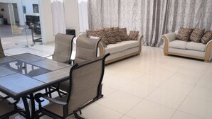 A modern living room with two sofas, a dining table, and chairs.