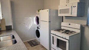 Una cocina equipada con lavadora y secadora integradas, estufa y microondas.