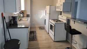 Una cocina compacta con alacenas blancas, un lavamanos, una estufa y un microondas.