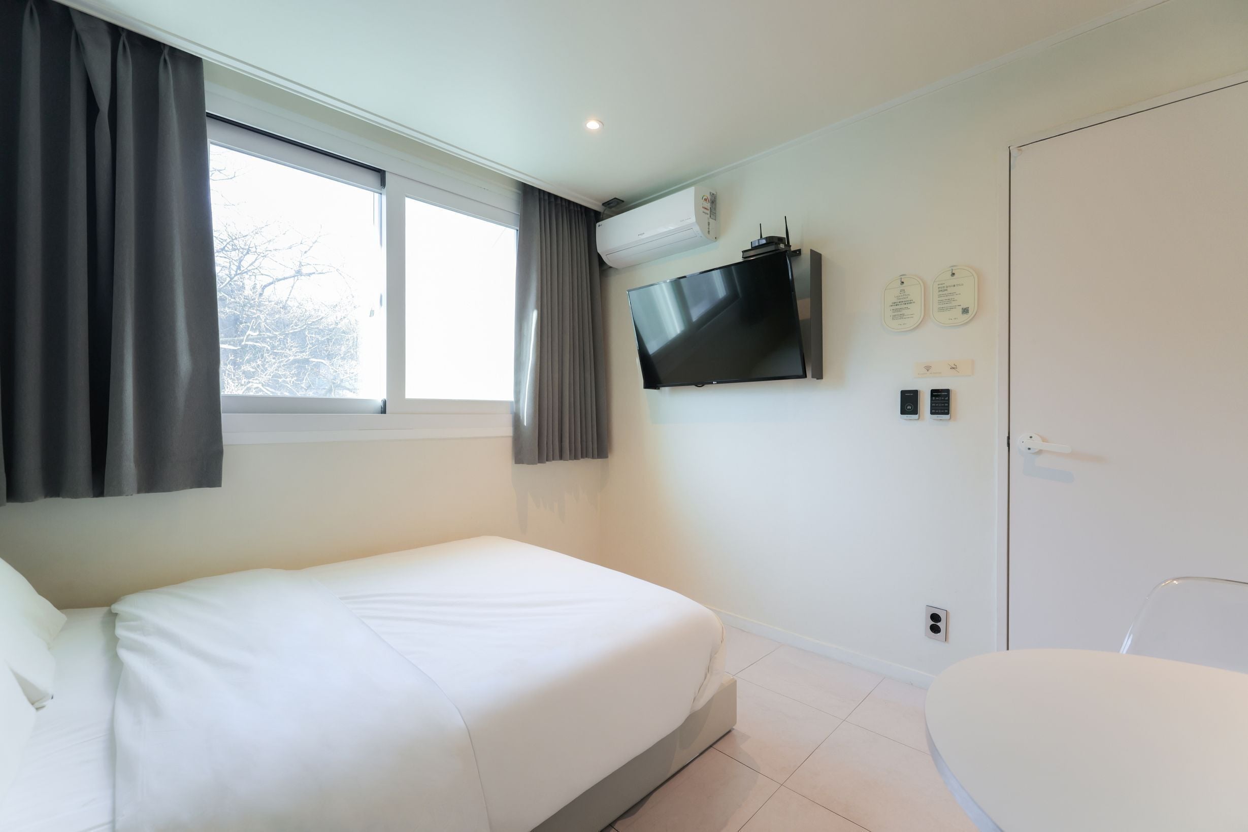 A modern hotel room with a bed, a TV mounted on the wall, and a door with a handle.