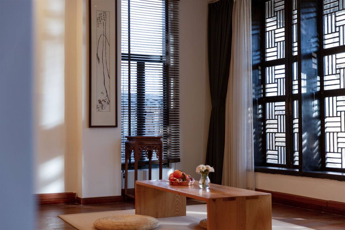 A traditional room with a wooden table, a vase with flowers, and a framed artwork on the wall.