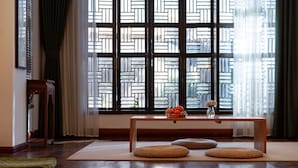Una habitación con una mesa de madera, esteras tejidas y una ventana con un diseño geométrico.