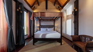 Una cama con dosel con ropa de cama blanca, un banco de madera y un candelabro.