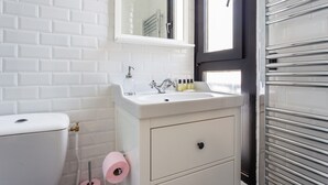 A bathroom with a white toilet, a sink with toiletries, a mirror, and a towel rack. - Serene Apartment - 1br/4p - Place de la Bastille (Paris)