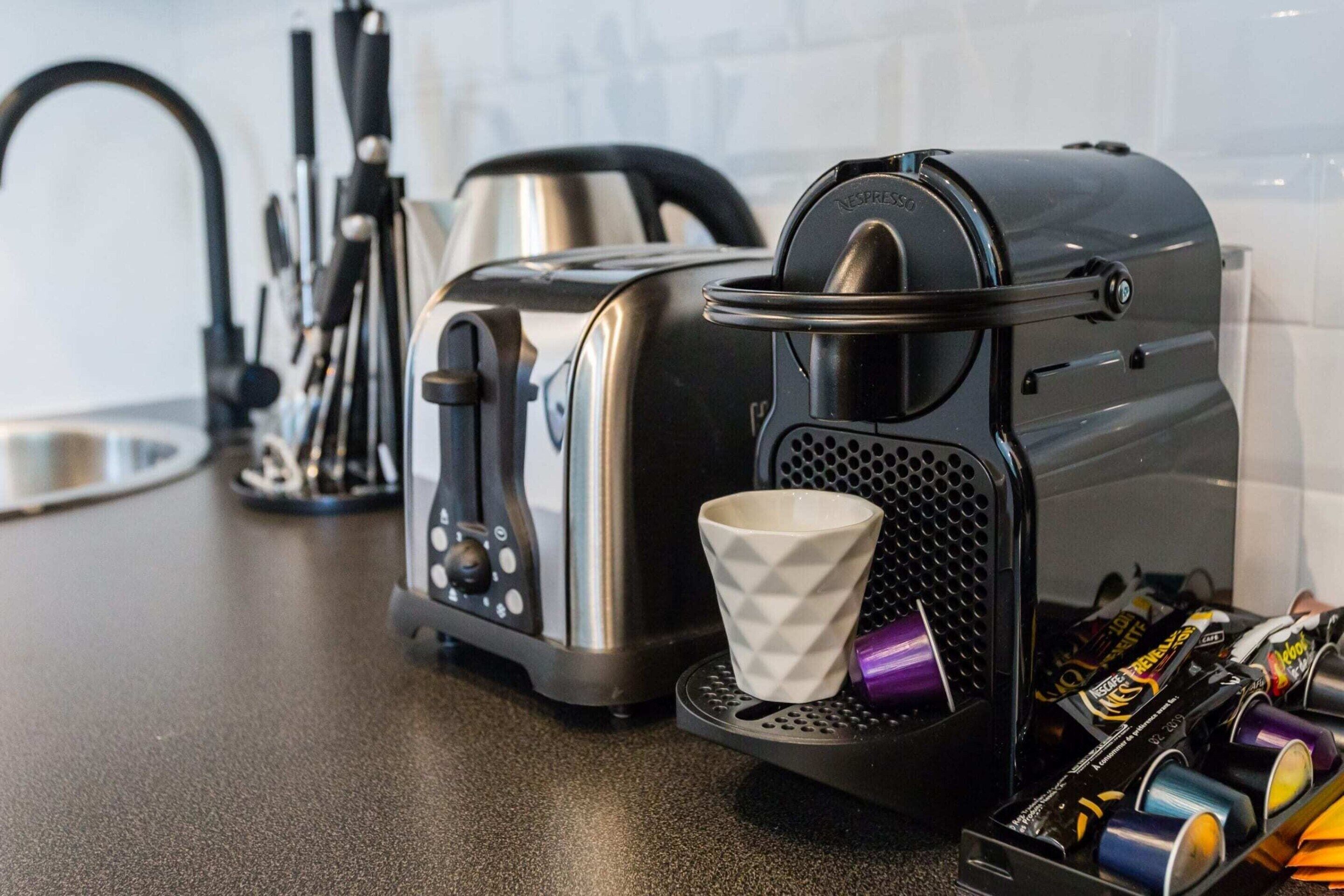 A kitchen with a coffee machine, a toaster, and a cup on the counter.