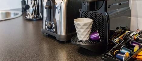 A kitchen with a coffee machine, a toaster, and a cup on the counter.