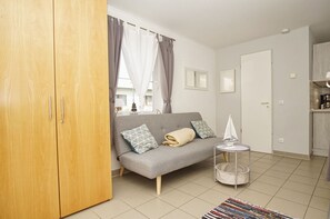 A modern living room with a grey sofa, wooden wardrobe, and a small round table with a model ship.