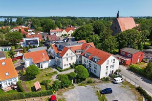 A residential area with houses, a church, and a parking lot. - 1-room vacation apartment near the harbor with a small garden - Haus Windland FeWo 24 - House (Wiek)