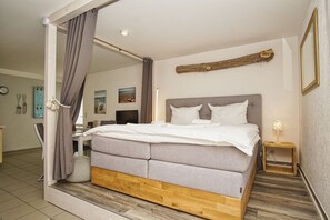 A modern bedroom with a large bed, a wooden headboard, and a mirror.