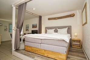 A modern bedroom with a large bed, a wooden headboard, and a mirror.