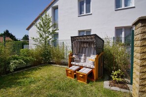 A house with a garden, a wooden bench, and a striped canopy.