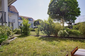 Un quartier résidentiel avec une cour gazonnée, une clôture en métal et un bâtiment doté d’un toit en tuiles.