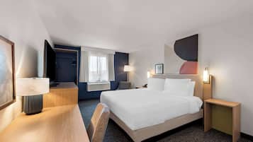 A hotel room with a bed, bedside tables, a desk, a chair, a window with curtains, and a wall-mounted artwork.