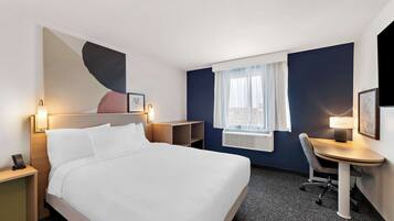 A hotel room with a bed, bedside tables, a desk, and a chair.