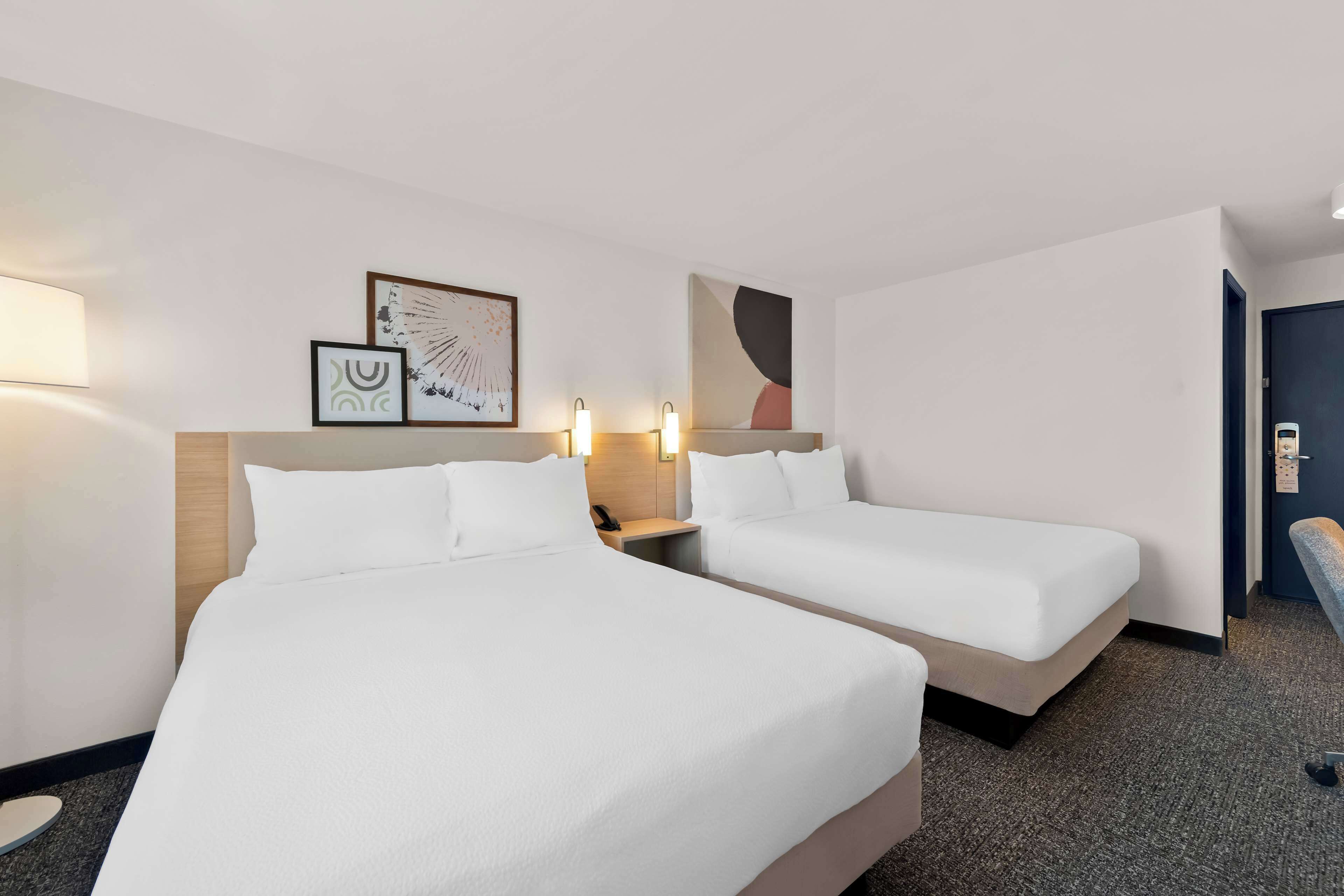 Ein Hotelzimmer mit zwei Betten, einem Nachttisch und Wandbildern.