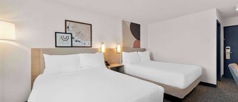 Ein Hotelzimmer mit zwei Betten, einem Nachttisch und Wandbildern.