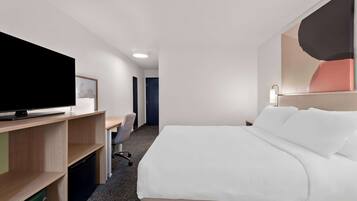 Habitación de hotel con cama, escritorio con silla, televisión y una obra de arte colgada en la pared.