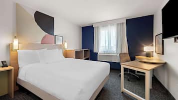 A hotel room with a large bed, bedside tables, a desk, and a chair.