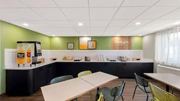 A modern kitchen area with a counter, a coffee machine, and a sign that reads "Delight in the day."