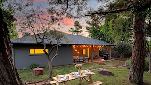 A house with a patio set for dining, surrounded by trees and a garden. - West Sedona modern home with thunder mountain views/patio is a private oasis/Pet (Sedona)