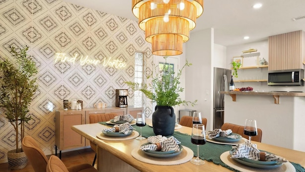 A dining area with a long table, chairs, a vase with greenery, and a kitchen in the background. - West Sedona modern home with thunder mountain views/patio is a private oasis/Pet (Sedona)