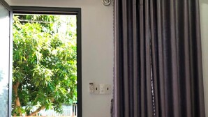 A bedroom with a bed, a window, and a view of greenery outside. - Homestay Lagi (Phuoc Hoi)