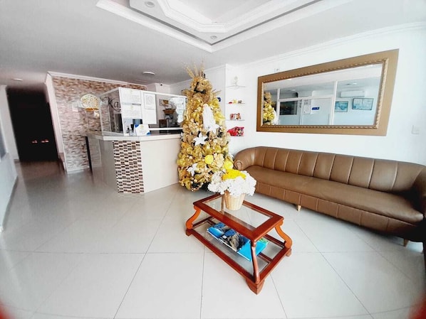 A living room with a brown sofa, a glass coffee table, and a decorative golden tree. - Hotel Karin (Riohacha)