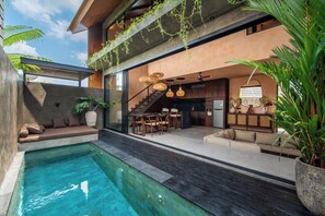 Un'area esterna moderna con piscina, posti a sedere e una scala che conduce a un livello superiore.