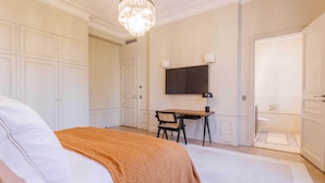A bedroom with a bed, a desk, a television, and a bathroom. - Luxury Mansion With Garden in Heart of Neuilly (Neuilly-sur-Seine)