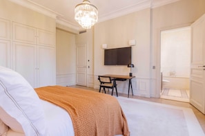 Un dormitorio con cama, escritorio, televisor y baño.