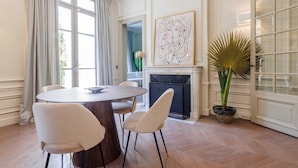 A dining area with a round table, four chairs, a fireplace, and a large potted plant. - Luxury Mansion With Garden in Heart of Neuilly (Neuilly-sur-Seine)
