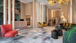 A modern lobby with a reception desk, seating area, and decorative elements like a giraffe statue and a chandelier. - Hilton Garden Inn Athens Syggrou Avenue (Kallithea)